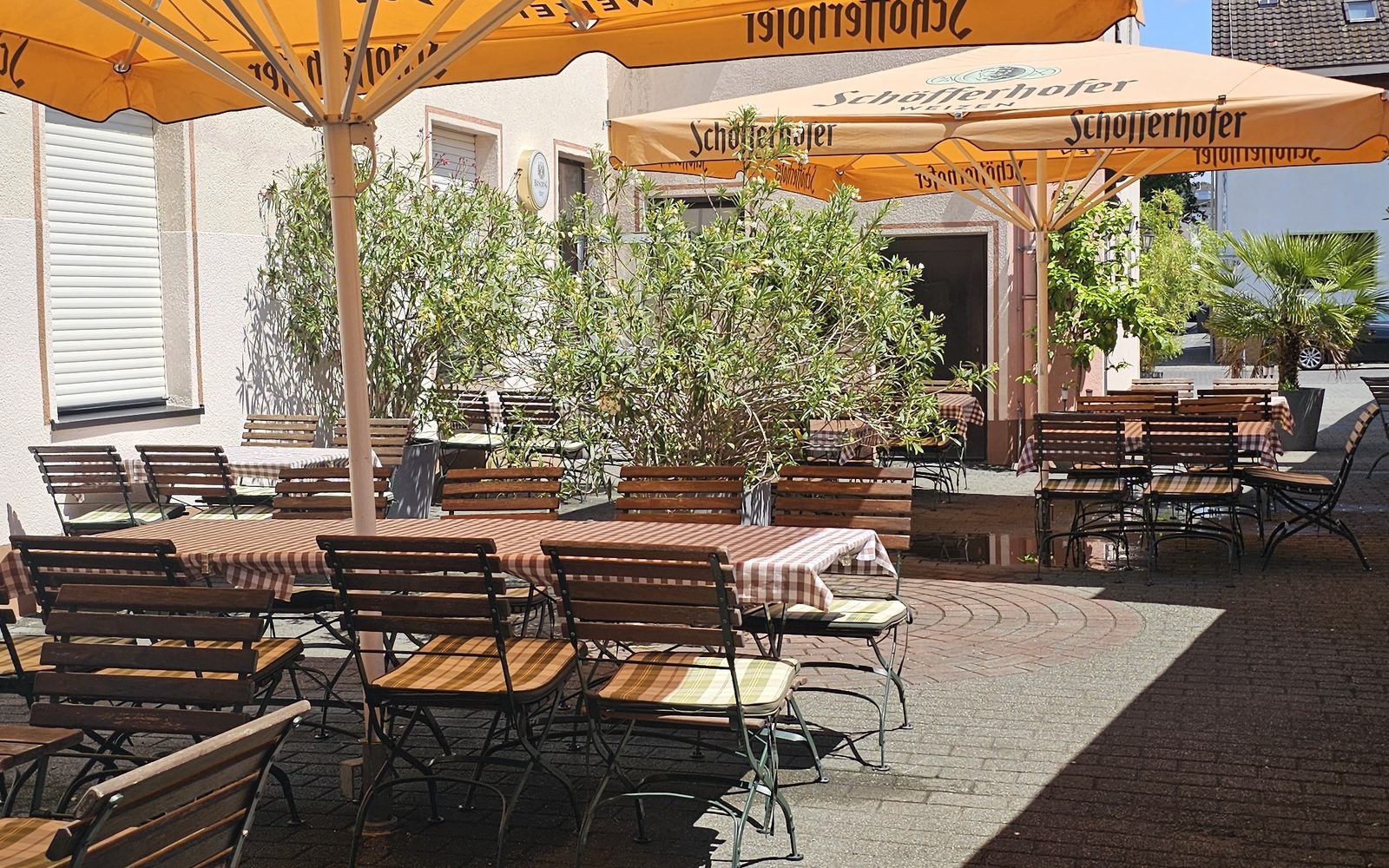 Der Biergarten von Bei Anna mit Sonnenschirmen, Tischen und Pflanzen