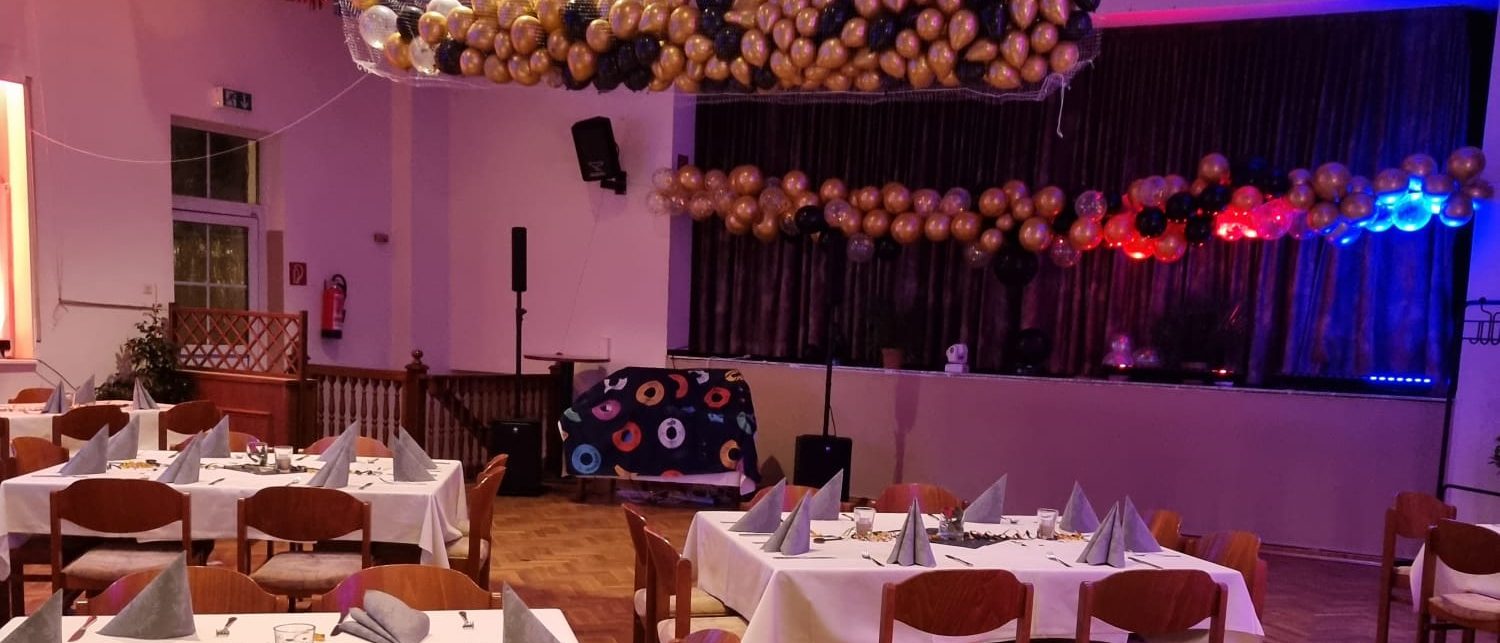 Der große Saal mit eingedeckten Tischen, Luftballons und festlicher Deko