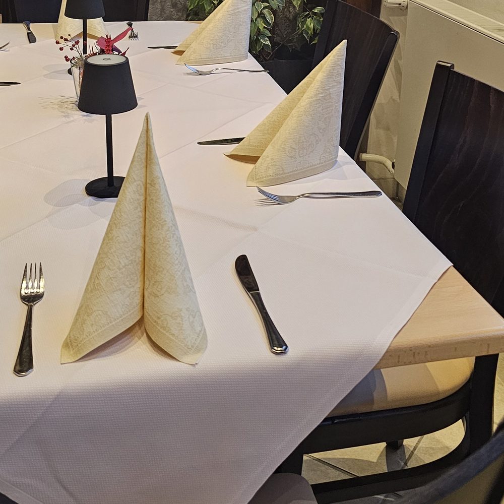 Eingedeckter Tisch mit gefalteten Servietten, Besteck und Tischlampe